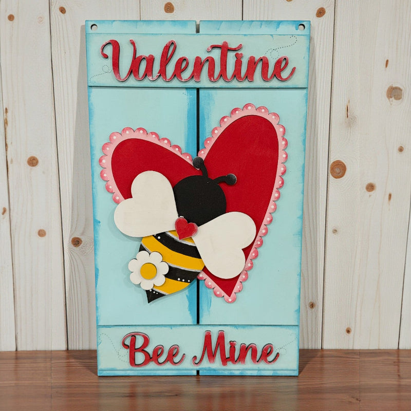 Valentine's Day card with a bee and heart design on a wooden surface