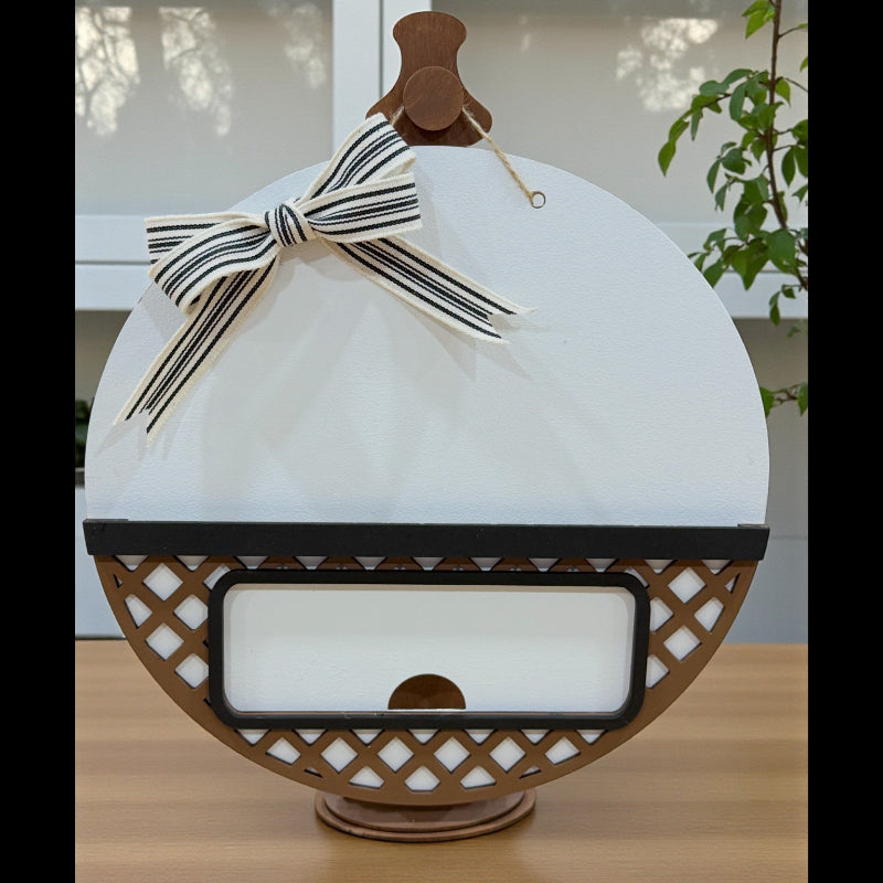 Unfinished round interchangeable door sign base made from layered wood, displayed unpainted with insert opening visible.