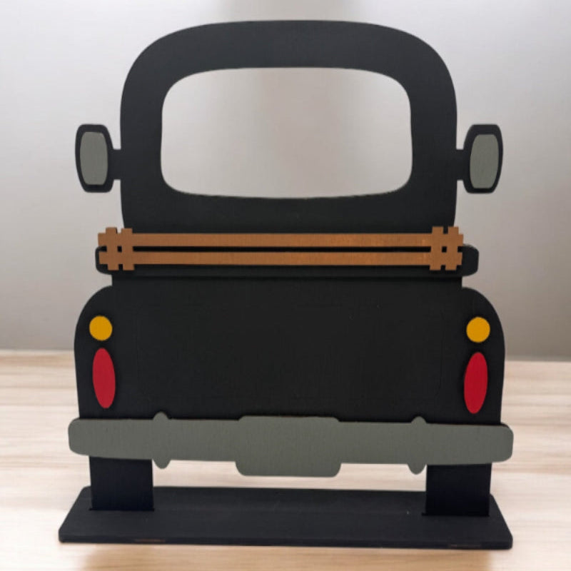 A wooden DIY farmhouse truck base with a slotted base and decorative elements on the back panel, designed for seasonal inserts.
