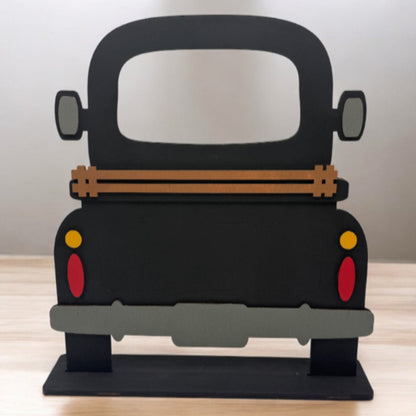 A wooden DIY farmhouse truck base with a slotted base and decorative elements on the back panel, designed for seasonal inserts.