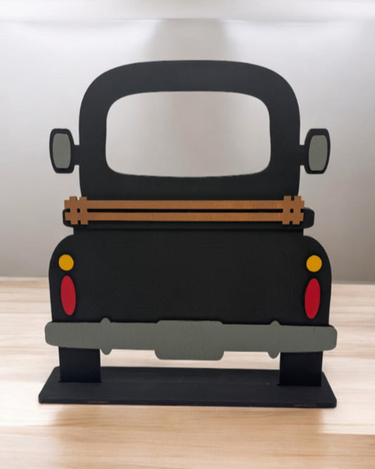 A wooden DIY farmhouse truck base with a slotted base and decorative elements on the back panel, designed for seasonal inserts.