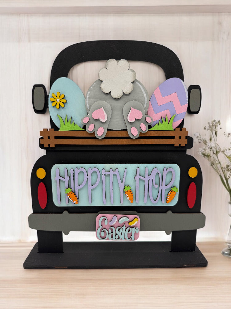 A decorative wooden Easter-themed truck insert with a bunny and eggs design, featuring a 'Hippity Hop' sign and a license plate, intended for painting and customization.