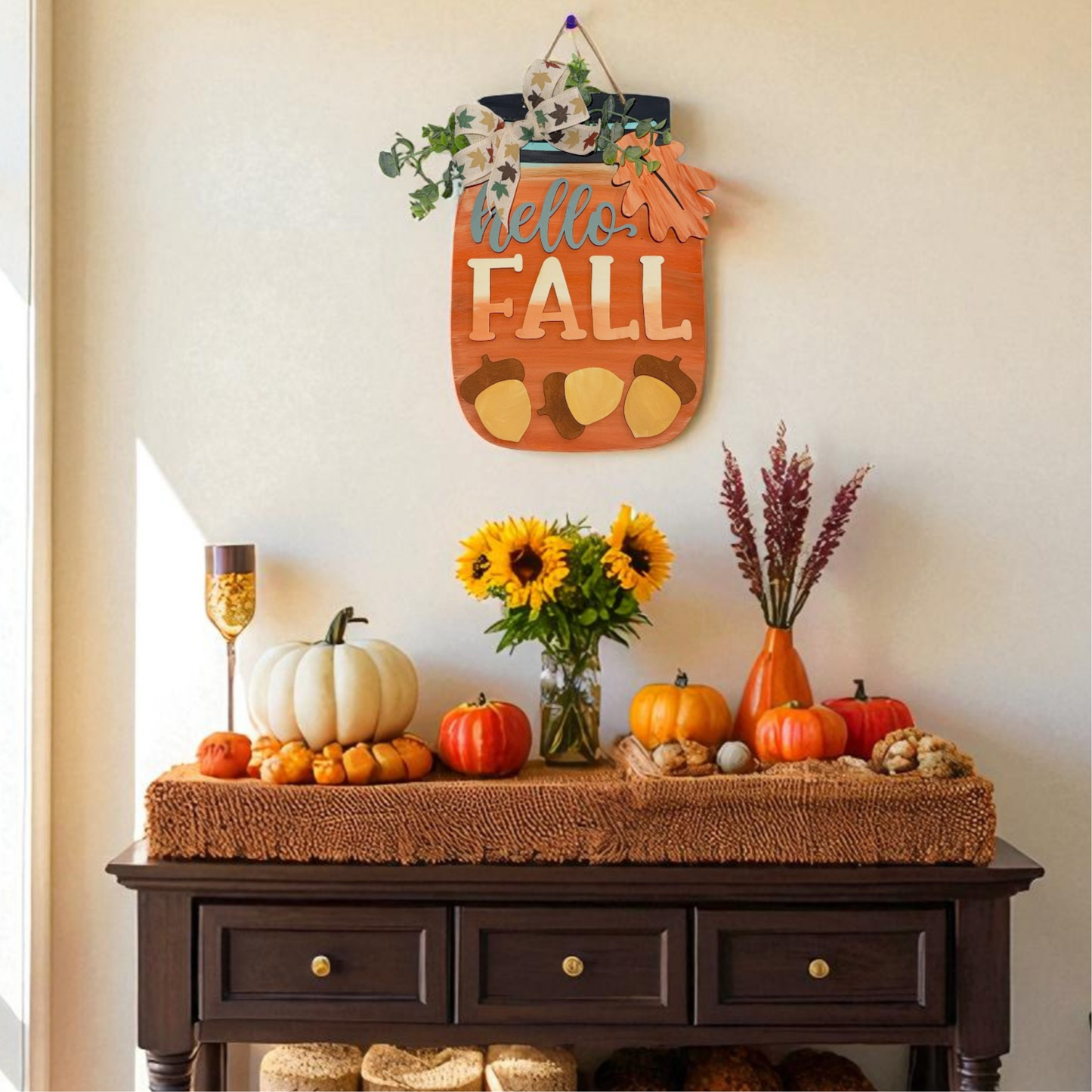 Decorative autumn-themed console table with pumpkins, sunflowers, and a 'Hello Fall' sign.