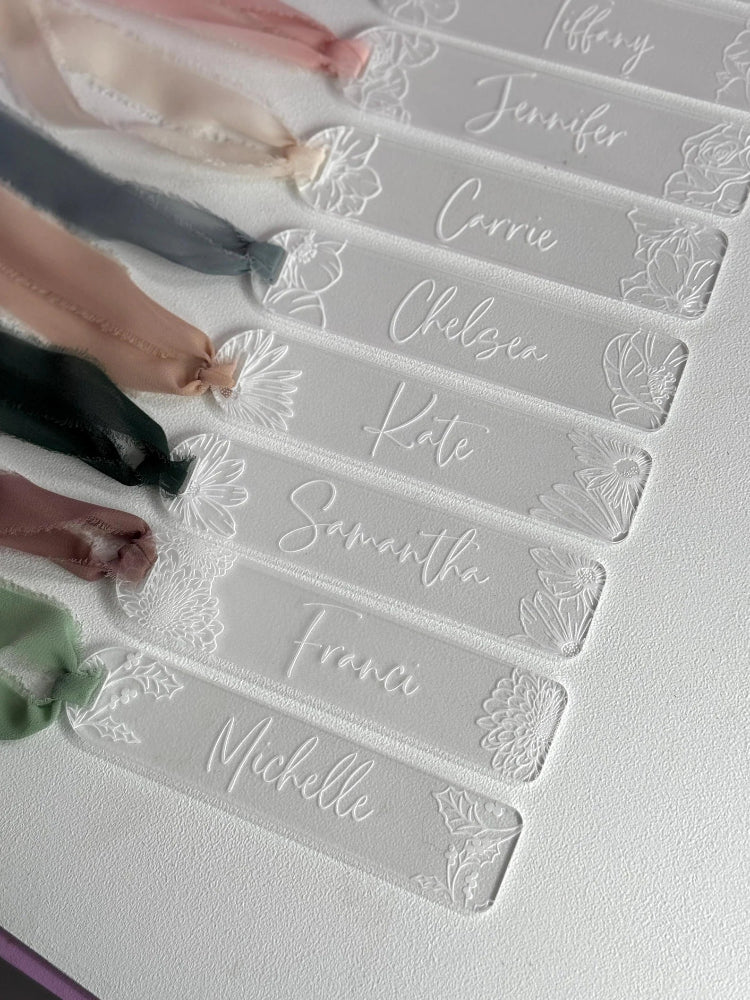 Names embossed on clear acrylic name tags with decorative elements.